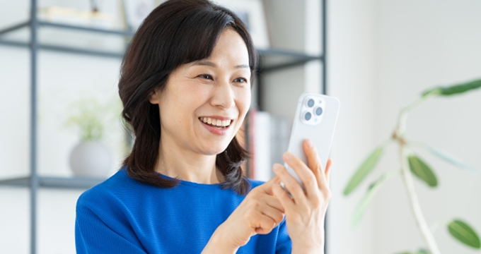 スマートフォンを見つめて喜ぶ女性